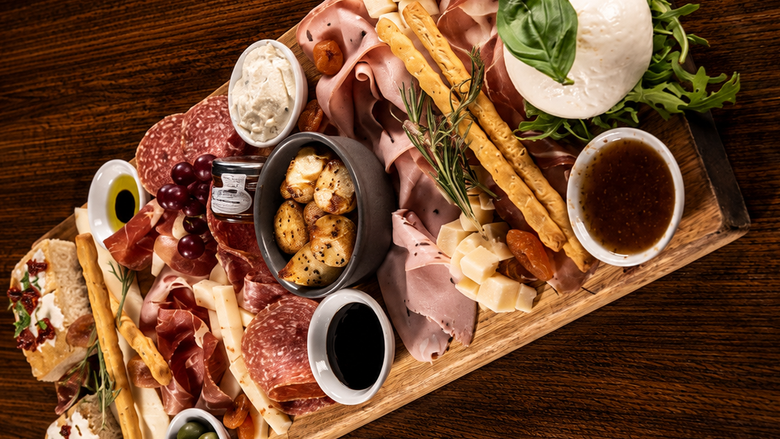 Veeno Italian sharing board with cured meats, mozzarella, olives and breadsticks — overhead view